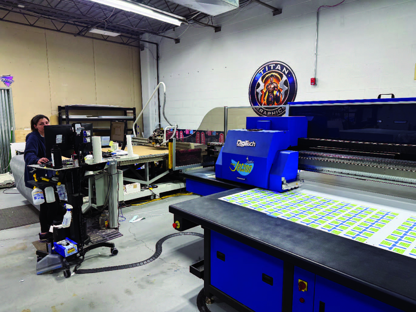 Active production at Titan Graphics showing UV flatbed printer and cutting equipment